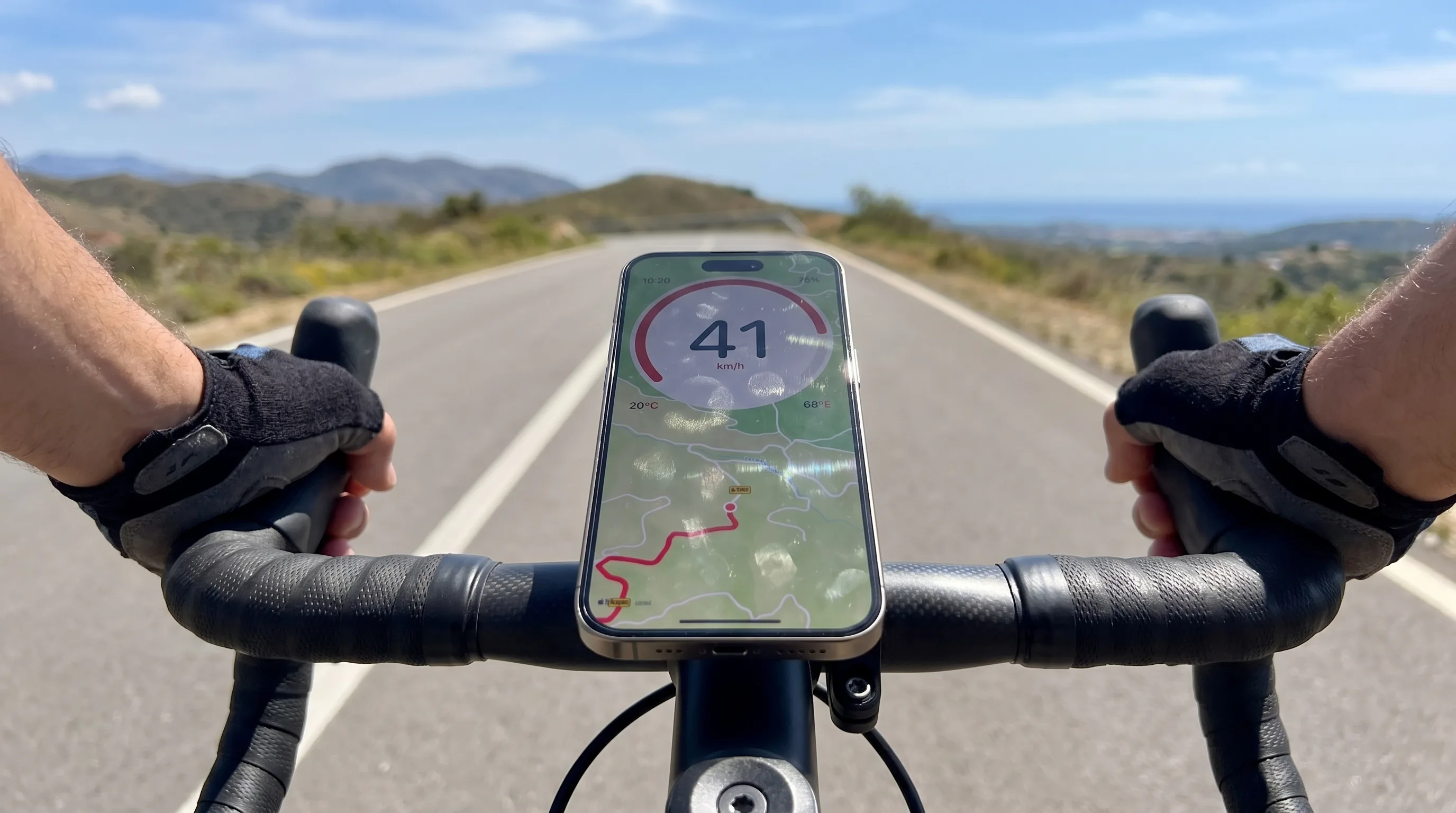 GPS Speedometer running on an iPhone in an out-front stem mount on a road bike, scenic open road extending ahead