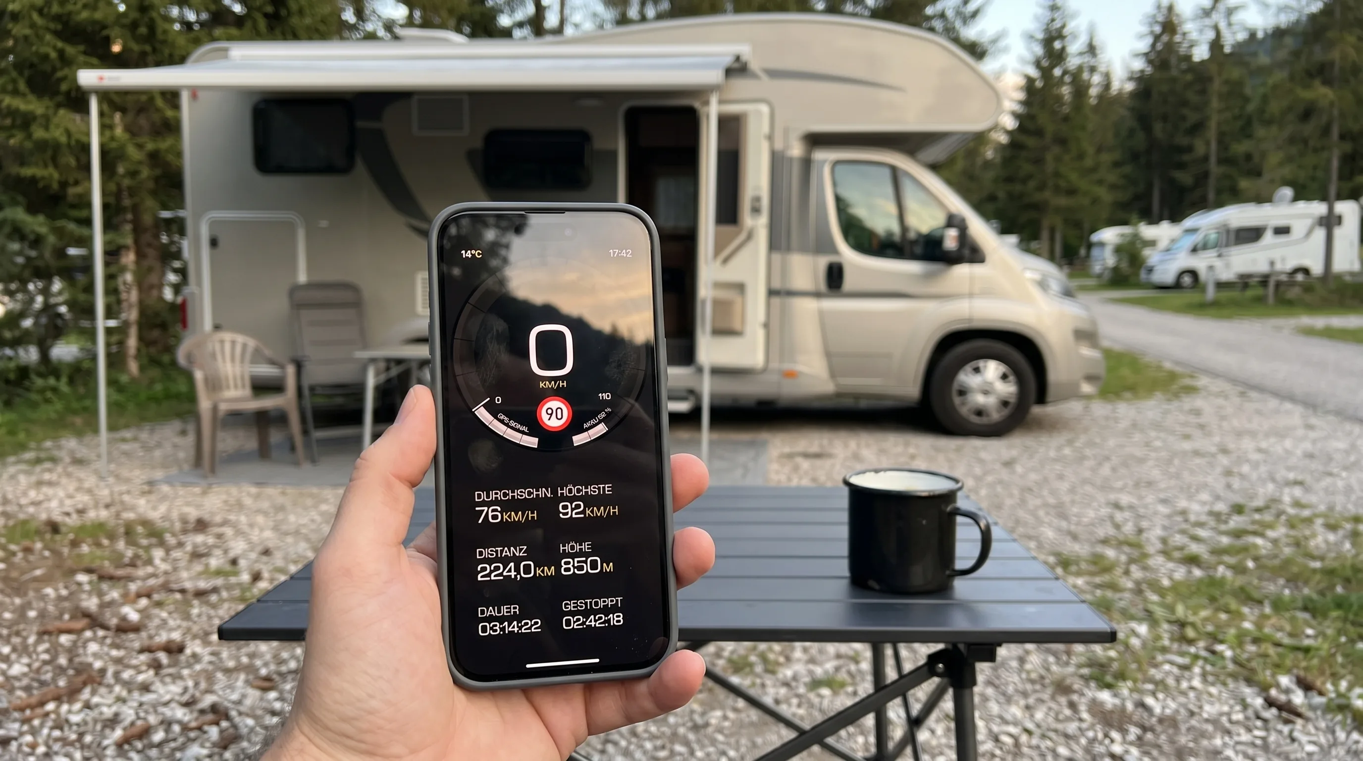 Ein deutsches Wohnmobil steht zur goldenen Stunde auf einem Alpen-Campingplatz, das iPhone zeigt die Fahrt-Zusammenfassung von GPS Speedometer auf Deutsch mit metrischen Einheiten