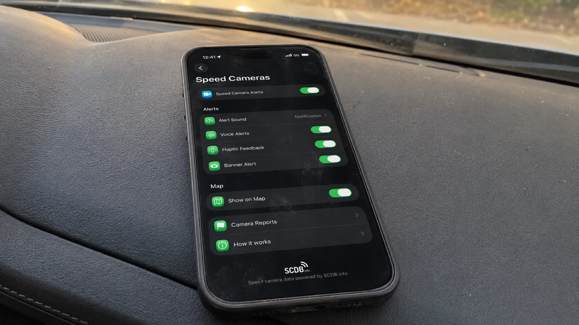 The Speed Cameras settings screen — master alert toggle, four independently switchable alert channels (Alert Sound, Voice Alerts, Haptic Feedback, Banner Alert), Show on Map, and Camera Reports access. Database powered by SCDB.info.